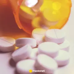 Białe tabletki, w tym lorazepam, wysypują się z pomarańczowego pojemnika.