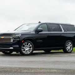 Czarny Chevrolet Suburban High Country z chromowanymi felgami stoi na parkingu.