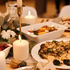 Festlich gedeckter Tisch mit Kerzenlicht, Granatapfel, Cranberry-Sauce und einem Teller mit geröstetem Gemüse – ein gesundes Weihnachtsessen.