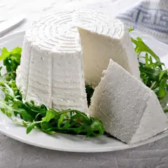 Formaggio fresco su un piatto bianco con rucola, ideale per chi cerca alimenti senza caseina.
