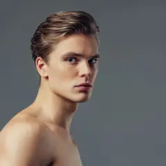 Joven con pelo liso hombre, ojos azules y piel clara, mirando a la cámara con expresión seria.