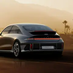 Elegancki Hyundai Ioniq 6 z charakterystycznym pasem świateł z tyłu, zaparkowany na tle lotniska i palm.