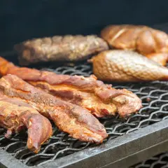 Plusieurs morceaux de filet de porc fumé, dorés et juteux, reposent sur une grille de barbecue, prêts à être dégustés.