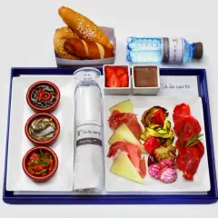 Pyszne jedzenie w samolocie: przystawki, sery, wędliny, pieczywo, owoce i deser.
