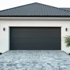 Modernes Haus mit neuem, dunklem Garagendach und gepflasterter Einfahrt.