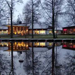 Vinterkväll vid Best Western Norra Vättern. Hotellets ljus speglas i vattnet, omgivet av kala träd.