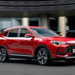 MG ZS HEV rosso in movimento, un'auto moderna che affronta la strada senza problemi.