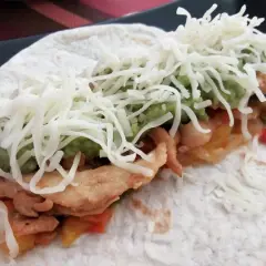 Fajitas de pollo y queso, con guacamole y pimientos salteados, envueltas en tortilla.
