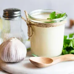 Słoik domowego aioli, czosnek, cytryna i natka pietruszki – składniki idealnego sosu.