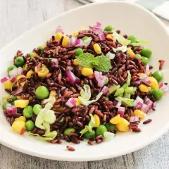 Insalata colorata di riso venere freddo con piselli, mais, cipolla rossa e lattuga. Un'idea fresca su come condire il riso venere freddo.