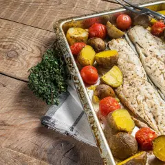 Coda di rospo al forno con patate e pomodorini, un piatto semplice e gustoso, pronto per essere servito.
