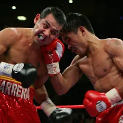 A boxer wearing red shorts with "BARRERA" emblazoned on them takes a hit.