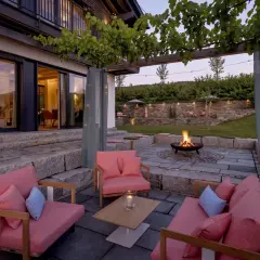 Gemütliche Lounge-Möbel und ein Feuerkorb laden zum Entspannen ein. Die Weinreben über der Pergola und Lichterketten schaffen eine romantische Atmosphäre, perfekt, um die Terrasse zu dekorieren.