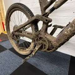 Mud-caked mountain bike rear triangle and wheel. This looks like it will be an expensive bike service cost.