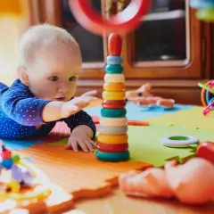 Dziecko bawi się kolorowymi, potencjalnie niebezpiecznymi zabawkami dla dzieci, takimi jak wieża z kółek i spiralna kula.