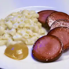 En tallrik med stuvade makaroner, skivad falukorv och en klick senap. En snabb och klassisk svensk måltid.