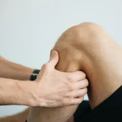 Fizjoterapeuta bada kolano, pomagając zrozumieć, jak wzmocnić więzadła w kolanie.