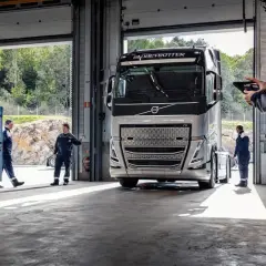 Mechanicy w serwisie obsługują nowoczesną ciężarówkę Volvo FH4. Jeden z nich sprawdza coś na tablecie.