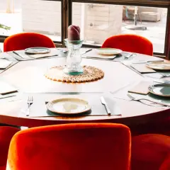 Okrągły stół z nakryciami i pomarańczowe, welurowe krzesła tworzą elegancką aranżację. Idealne, jakie krzesła do okrągłego stołu dla wyrafinowanej jadalni.