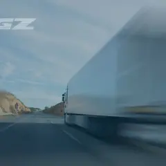 art 12 561 we 2006 opis. Ciężarówka TGZ pędzi autostradą, krajobraz rozmyty przez prędkość.