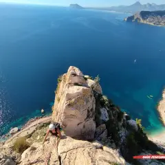 Escaladora en el Peñón de Calpe, con el mar azul y la costa al fondo.
