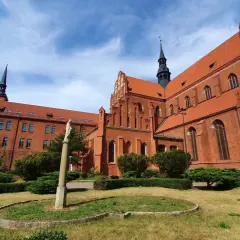 Gotycka ceglana katedra w Pelplinie, serce Kociewia, z zielonym ogrodem i figurą Matki Boskiej.
