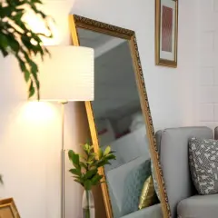 Ein großer Spiegel und eine Stehlampe helfen, die dunkle Wohnung heller zu machen. Ein Sofa mit Kissen und eine Pflanze vervollständigen die Szene.