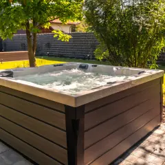 Relaks w ogrodzie przy bąbelkach jacuzzi. W tle widać basen i huśtawkę.