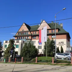 Budynek Akademii Nauk Stosowanych w Nowym Targu z polską flagą.