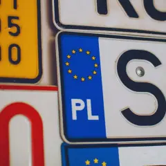 Zbliżenie na tablice rejestracyjne. Widoczne oznaczenia PL i SK, a także fragmenty innych tablic.