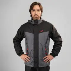 Hombre posando con una prenda impermeable que protege de la lluvia, chaqueta de dos tonos gris y negro con detalles rojos.