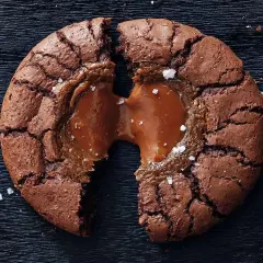 En brownie cookie med flytande karamell som rinner ut, strödd med havssalt.