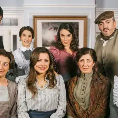 Grupa ośmiu osób w strojach z epoki, pozująca do zdjęcia w pomieszczeniu.