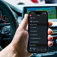 Dłoń trzyma smartfon z aplikacją, gdzie można dokonać **cepik sprawdzenie OC**. W tle widać wnętrze samochodu.