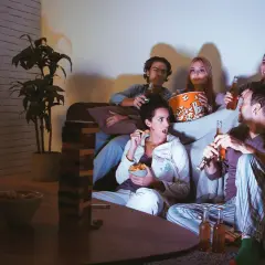 Ragazzi sul divano, popcorn e birra per una serata film.