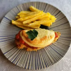 Delicioso pollo a la parmesana con papas fritas crujientes, servido en un plato rayado.