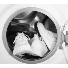 Deux baskets blanches sont prêtes pour leur entretien dans un lave-linge.