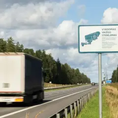 Znak informuje o monitoringu na Litwie. Ciężarówka mija znak z kamerą na autostradzie.