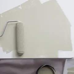 Application d'une peinture beige sur du mélaminé blanc avec un rouleau. Le résultat est une surface lisse et uniforme.