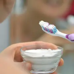 Mano tiene una spazzolino con dentifricio e una ciotola con polvere bianca, forse per sbiancare i denti con perossido di idrogeno.