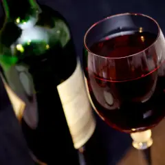 Czerwone wino w kieliszku obok butelki. Ile promili po lampce?
