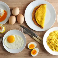 Różne rodzaje jajek na talerzach: jajko sadzone, jajecznica, omlet, jajko w koszulce, gotowane i surowe.