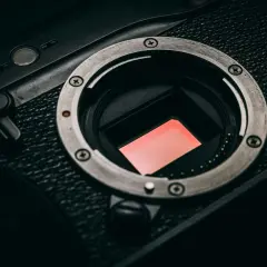 Zbliżenie na matrycę **cmos** aparatu fotograficznego. Czerwona powierzchnia sensora odbija światło.
