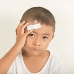Bambino con cerotto sulla fronte, forse a seguito di un trauma cranico.