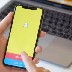 Dłoń trzyma smartfon z logo Snapchata. Widoczny ekran logowania, który może pomóc w procesie jak usunąć konto na snapie.