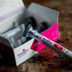 Pojedynczy wstrzykiwacz Mounjaro (tirzepatide) leży obok otwartego pudełka z lekami.