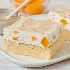 Saftiger Pfirsich Schmand Kuchen mit zarter Sahne und Zimt bestreut. Ein Genuss für jeden Anlass.