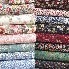 Stacks of folded shirts showcase vibrant, small floral prints, a hallmark of what is liberty fabric.