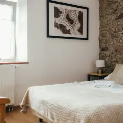 Przytulna sypialnia z kamienną ścianą, łóżkiem i oknem.