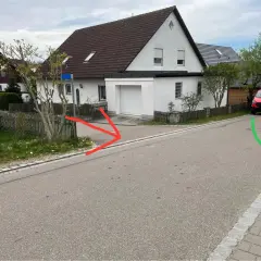 Ein roter Lieferwagen parkt auf der rechten Straßenseite, während rote Pfeile auf eine Einfahrt und ein grüner Pfeil auf einen Gullydeckel zeigen. Das Schild "rechts vor links" ist nicht sichtbar.